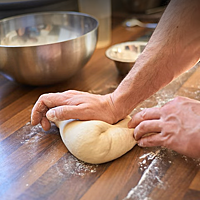 Ein Teigling wird auf der Arbeitsfläche mit der Hand geknetet.