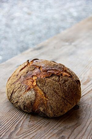 Ein kräftig ausgebackenes Almweizen auf einem rustikalen Holztisch.