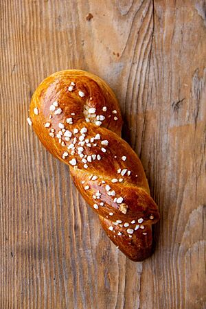 Ein mit Hagelzucker bestreuter Flachswickel in der typisch verdrehten Form liegt auf einem Holztisch.