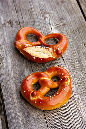 Almbrezeln. Zwei mit Salz bestreute Laugenbrezel mit und ohne eingeschnittenem Brezelbauch.