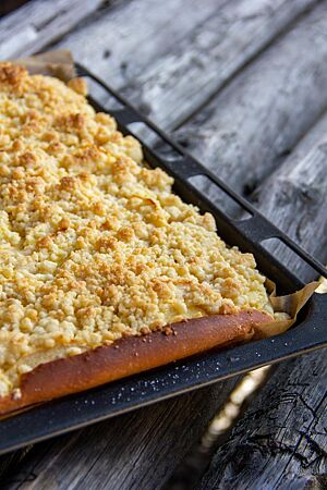 Almhefekuchen. Der fertig ausgebackene Almhefekuchen mit Streuseln auf der Oberfläche liegt auf einem Kuchenblech.