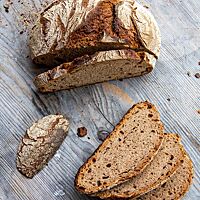 Ein in Scheiben geschnittenes Emmer-Dinkel-Brot lässt die kleinporige Krume unter der dicken, knusprigen Kruste erkennen.