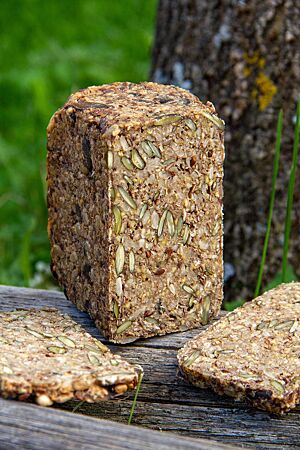 Ganzundgar-Brot. Ein saatenreiches Kastenbrot liegt in der freien Natur auf einem Holztisch.