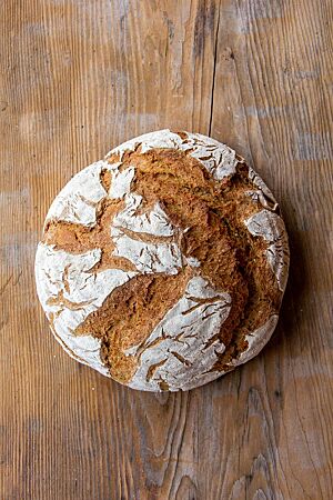 Das runde Bauernbrot hat eine bemehlte, rustikal aufgerissene Kruste.