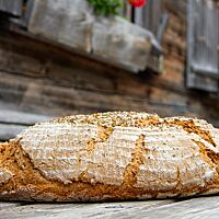 Das im Holzofen gebackene Kärntner Bauernbrot hat eine matte, leicht bemehlte Kruste und Brotgewürz auf der Oberseite.