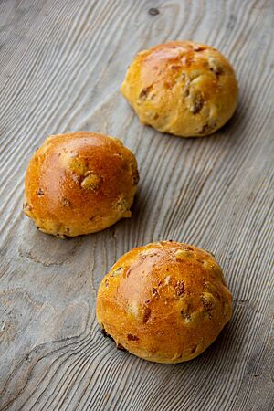 Krentenbollen (holländische Rosinenbrötchen). Unter der glatten, stark glänzenden Kruste der Krentenbollen sind die Rosinen mit kleinen Wölbungen sichtbar.