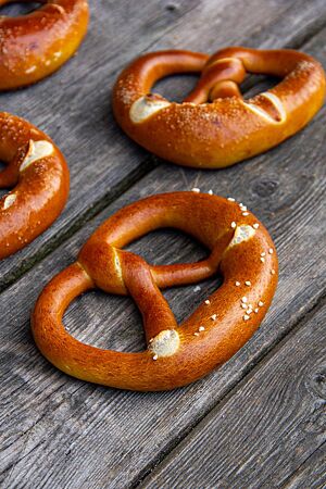 Die mit Brezelsalz bestreuten, glänzenden Laugenbrezeln liegen auf einem rustikalen Holztisch.