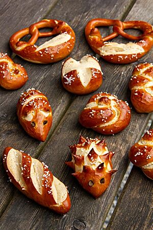 Laugengebäck. Fantasievoll geformtes Laugengebäck liegt auf einem Holztisch – als Igel, Maus, Brezel, Knoten usw.