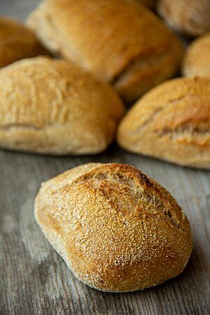 Die goldbraun ausgebackenen und rustikal aufgerissenen Weizenbrötchen sind auf der Oberfläche mit Grieß bestreut.