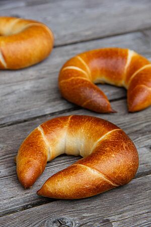 Milchhörnchen. Goldbraun ausgebackene Hörnchen liegen auf einem rustikalen Holztisch.