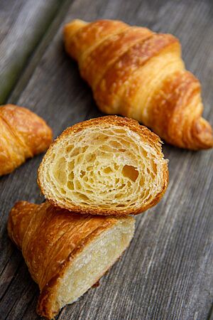 Plunderteig für Croissants: feinsplittrig und buttrig. <p>Ein Croissant im Querschnitt zeigt die buttrige, tourierte Krume.</p>
