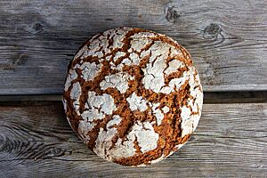 Das kräftig ausgebackene, bemehlte Rauriser Roggenbrot liegt auf einem rustikalen Holztisch.