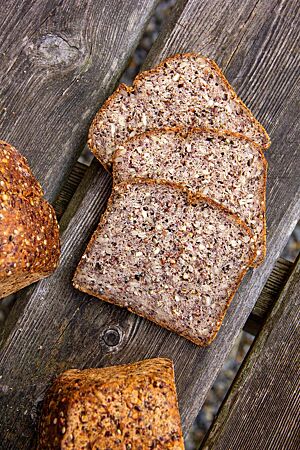 Buchweizen-Kastanien-Erdmandel-Brot (glutenarm). Im Anschnitt des Buchweizen-Kastanien-Erdmandel-Brotes werden Sonnenblumenkerne, Leinsaat, Buchweizenkörner sowie Hanf- und Chiasamen sichtbar.