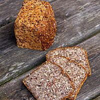 Das angeschnittene Buchweizen-Kastanien-Erdmandel-Brot offenbart jede Menge Saaten in der lockeren Krume.