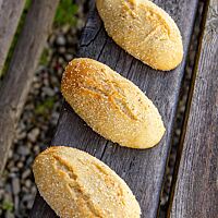 Die Maisbrötchen sind länglich geformt und haben eine goldgelb ausgebackene, leicht aufgerissene Kruste.