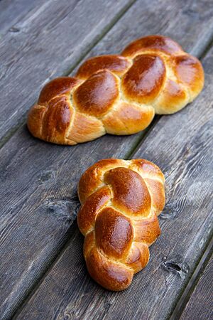 Ein goldbraun ausgebackener, geflochtener Butterzopf mit glänzender Oberfläche liegt auf einem rustikalen Holztisch.