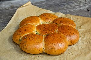 Acht kleine Weizenbrötchen liegen aneinandergebacken in Form einer Blüte auf Backpapier.