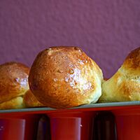 Goldbraun ausgebackene Brioche à tête mit glänzender Oberfläche sitzen in einer Muffinform.