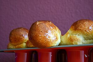 Goldbraun ausgebackene Brioche à tête mit glänzender Oberfläche sitzen in einer Muffinform.