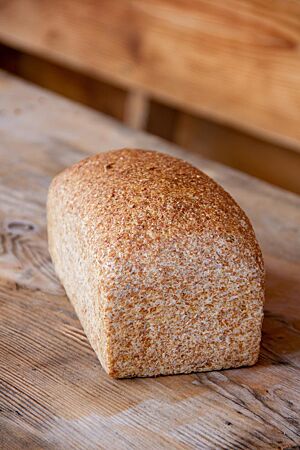 Ein lockeres, luftiges Weizenkeimlingsbrot mit glatter Oberfläche liegt auf einem Holztisch.