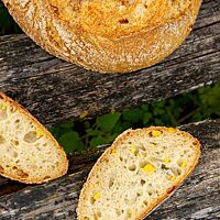 Im Anschnitt zeigt das Weizensauerteig-Mais-Brot ganze Maiskörner in der lockeren Krume.