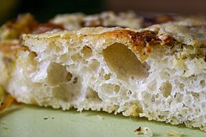 Angeschnitten zeigt die Focaccia ihre helle Krume mit der ungleichmäßigen Porung.