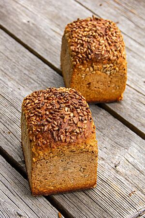 Zwei kräftig ausgebackene Dinkelvollkornbrote in Form von Kastenbroten sind auf der Kruste mit Sonnenblumenkernen bestreut.