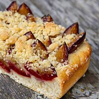 Im Anschnitt zeigt der Sauerteig-Blechkuchen den weichen, lockeren Hefeteigboden und die darüberliegenden Pflaumen und Streuseln.