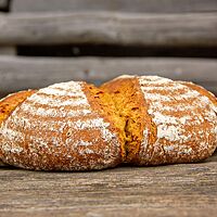 Das flache Kürbisbrot hat sich an den eingedrückten Stellen auf der Oberseite geöffnet und ist leicht bemehlt.