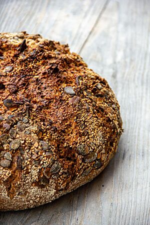 Das kräftig ausgebackene, rustikal aufgerissene Kleiebrot hat Sesam und Kürbiskerne auf der Oberfläche.