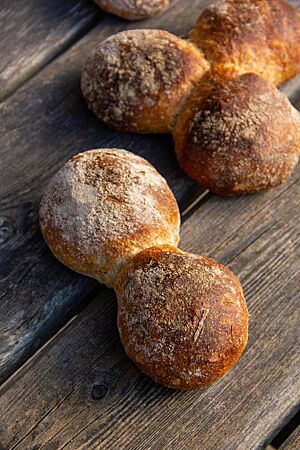 Die kräftig ausgebackenen Bürli in Form von Doppelbrötchen liegen auf einem rustikalen Holztisch.