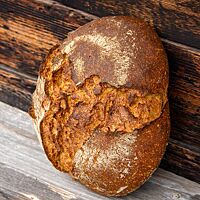 Das König-Thomas-Brot hat eine kräftig ausgebackene, rustikal aufgerissene Kruste mit leichten Mehlspuren.