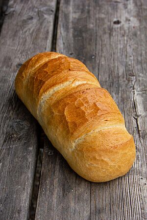 Ungarisches Hausbrot (Hefevariante). Das hellbraun ausgebackene Ungarische Hausbrot hat eine längliche Form und drei parallele Einschnitte auf der Oberseite.