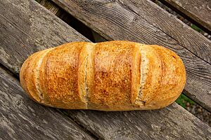 Ungarisches Hausbrot (Sauerteigvariante). Das hellbraun ausgebackene Ungarische Hausbrot hat eine längliche Form und drei parallele Einschnitte auf der Oberseite.