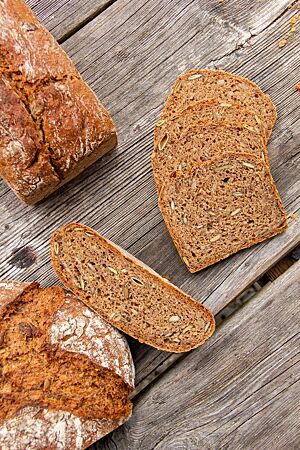 Saatenbrot mit Schwarzroggen: kann freigeschoben oder auch im Kasten gebacken werden. Sowohl freigeschoben als auch in Kastenform zeigt das angeschnittene Saatenbrot seine dunkelbraune, saftige Krume.