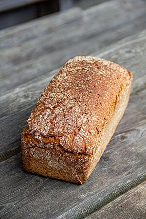 Jasminreisbrot. Das kastenförmige Jasminreisbrot mit glatter Oberfläche liegt auf einem rustikalen Holztisch.