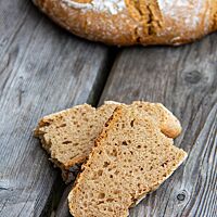Eine auseinandergebrochene Scheibe Roggen-Dinkel-Brot offenbart die kleinporige, lockere und saftige Krume.