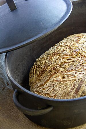 Das kräftig ausgebackene Weißbrot mit leicht bemehlter Kruste liegt im gusseisernen Topf.