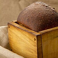Das dunkelbraune Honig-Salz-Brot wurde in einem Backrahmen gebacken und zeigt eine glatte, leicht glänzende Kruste.