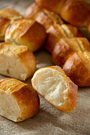 Semmellänge (Zeilensemmel): zart-knusprig und fluffig-weich. Ein an der Kontaktstelle auseinandergebrochenes Weizenbrötchen der Semmellänge zeigt die weiche, wattige Krume und die knusprige Kruste.