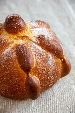 Pan de Muerto. Das goldbraun ausgebackene, mit Zucker bestreute Pan de Muerto liegt auf einem Leinentuch.