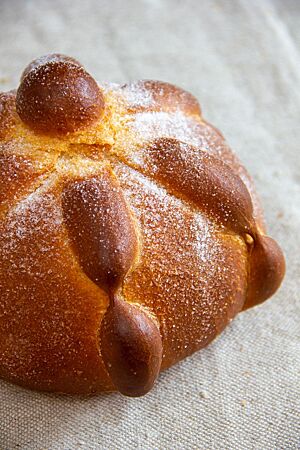 Das goldbraun ausgebackene, mit Zucker bestreute Pan de Muerto liegt auf einem Leinentuch.