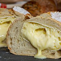 Aus dem Inneren des frisch nach dem Backen angeschnittenen Weißbrotes läuft der flüssige Camembert.