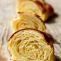 Ein mittig halbiertes Croissant zeigt die mittelporige, luftige Krume und die Vielzahl dünner Teigschichten unter der knusprigen Kruste.
