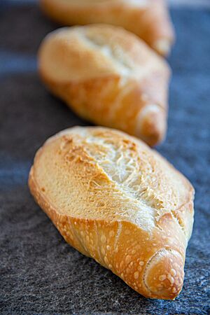 Mailänderbrötchen über Nacht. Das goldgelb ausgebackene Mailänderbrötchen hat sich an der Einschnittstelle sehr weit geöffnet.