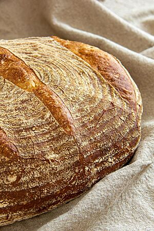 Das goldbraun ausgebackene, leicht bemehlte Pane Maggiore mit gefensterter Kruste liegt auf einem Leinentuch.