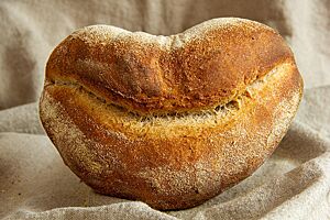 Ein Weizenmischbrot in Form von lächelnden Lippen liegt auf einem Leinentuch.