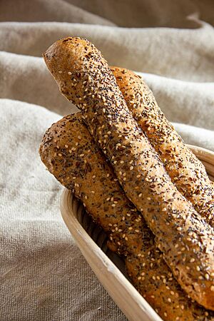 Dinkelvollkornseelen mit Mohn, Sesam, Leinsaat und Kümmel auf der Kruste liegen goldbraun ausgebacken in einem Gärkorb.