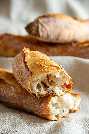Dinkelbaguettes: grobporig und äußerst aromareich. Ein auseinandergebrochenes Baguette lässt einen Blick auf die grobporige, helle Krume zu.