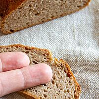 Zwei Finger liegen auf einer kleinen Brotscheibe und zeigen die Größe des Weinheimer Heidebrotes.